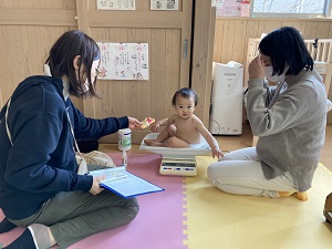 体重を測る幼児と見守る母