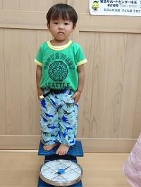 体重計の台に気を付けの姿勢で立っている男の子の写真