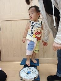 左横を見ながら体重計に乗っているアンパンマンのランニングシャツを着た男の子の写真