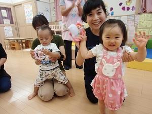 左に座っている母親の膝をまたがって立っている男の子、右に母親に両腕を持ち上げられ立っている笑顔の女の子の写真
