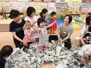 参加した親子の前にビリビリに破いた新聞紙があり、子供たちが新聞紙の中に入って喜んでいる写真