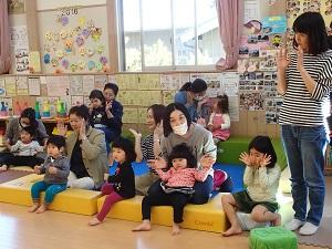 親子連れの参加者の皆さんが黄色いブロックや床に座って、手拍子をしている写真