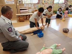 幼児の大きさの人形を使って心臓マッサージの練習を行っている参加者の写真
