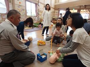 乳児の大きさの人形を使い、どの部位を押すのか太田救急救命士に確認している参加者の写真