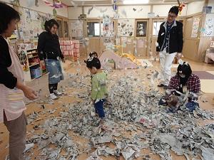 破った新聞紙が花吹雪みたいに舞っているのを楽しんでいる親子の写真