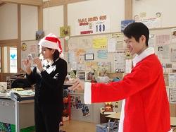 サンタクロースの帽子をかぶったユーゴ先生とサンタクロースの衣装を着たフェイス先生の写真