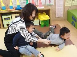 母親の膝の上に座っている男の子と床に寝そべっている男の子の写真