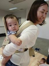 ベージュのおんぶ紐を使っておんぶ体験している一組の親子の写真