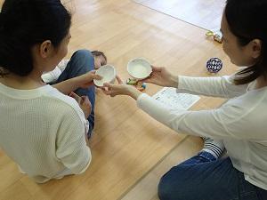 白いお茶碗に入ったサンプルを使って、離乳食の硬さを手で確かめる参加者達の写真