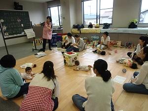 移動式黒板を使い離乳食の説明をする栄養士と、円状に座って話を聞く参加者達の写真