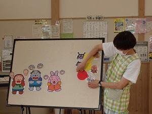 うさぎ、犬、猿の手が描かれたイラストと、アンパンマン、カレーパンマン、食パンマンとバイキンマンが描かれたイラストがホワイトボードに貼られている写真