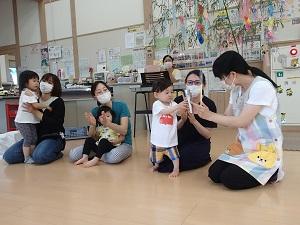 誕生日の子供にインタビューする職員、インタビューを受ける子供、子供の傍にいる保護者の写真
