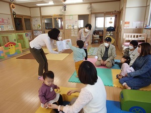 英語のしかけ絵本をめくる男児と見守る親子たち