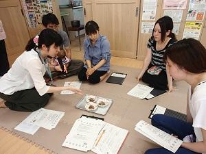 離乳食の見本を見せながら説明している栄養士と話を聞いている父親、母親の写真