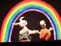いぬとうさぎのぬいぐるみが虹の下で手を繋いでいる様子の写真