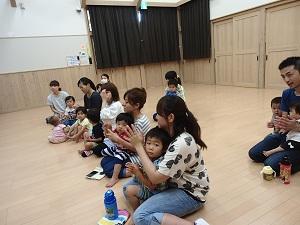 膝に子供を乗せた親たちが拍手をしている写真