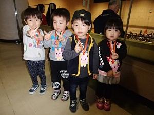 ピースサインをしてうさぎのメダルを首にかけて並んでいる4人の子供の写真