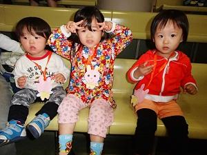 首にウサギのメダルをかけ、椅子に座っている3人の子供の写真
