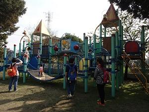 園庭にあるコンビネーション遊具で遊んでいる子ども達とその様子を近くで見守っているお母さん方の写真
