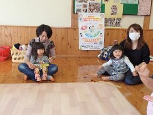 床に座った2組の母親と女の子の写真