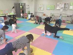 四つん這いから片足1本を伸ばしバランスをとる先生と親子たち