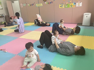 お腹に乗せた赤ちゃんに向かって腹筋をする先生とママたち