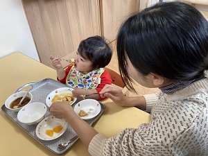 自分で食べる幼児と見守る母
