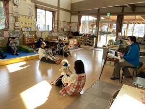 先生のピアノに合わせてお膝で滑り台遊びをする親子たち