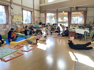 うつ伏せでバランス遊びをする先生と親子たち