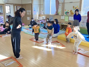 ラダーをジャンプする先生と真似をする幼児たち