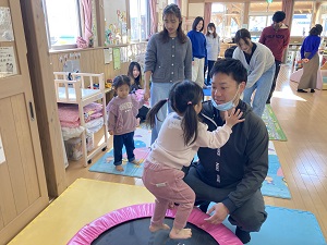 トランポリンをする幼児と見守る父