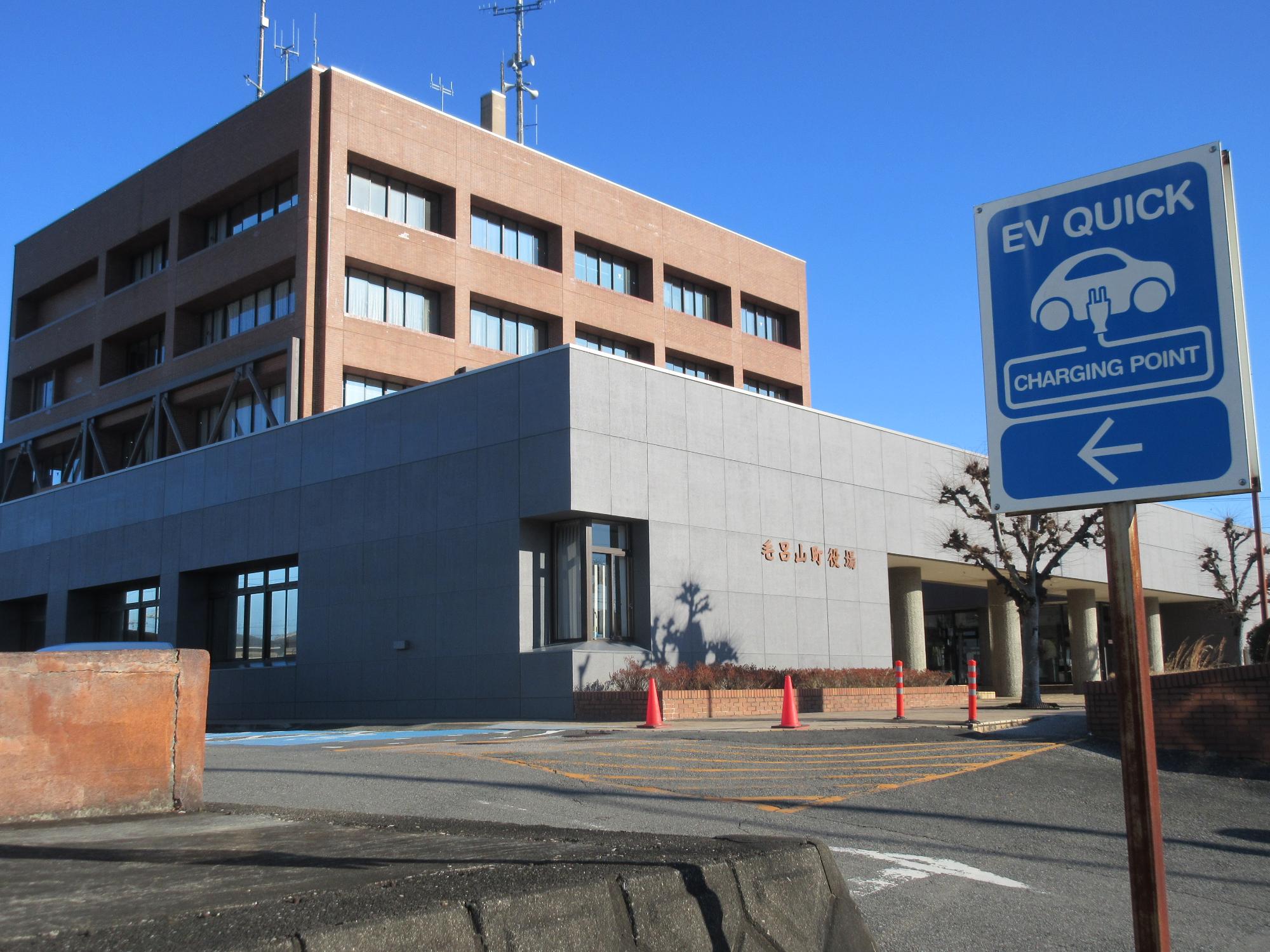 毛呂山町役場の外観と急速充電器の標識がある写真
