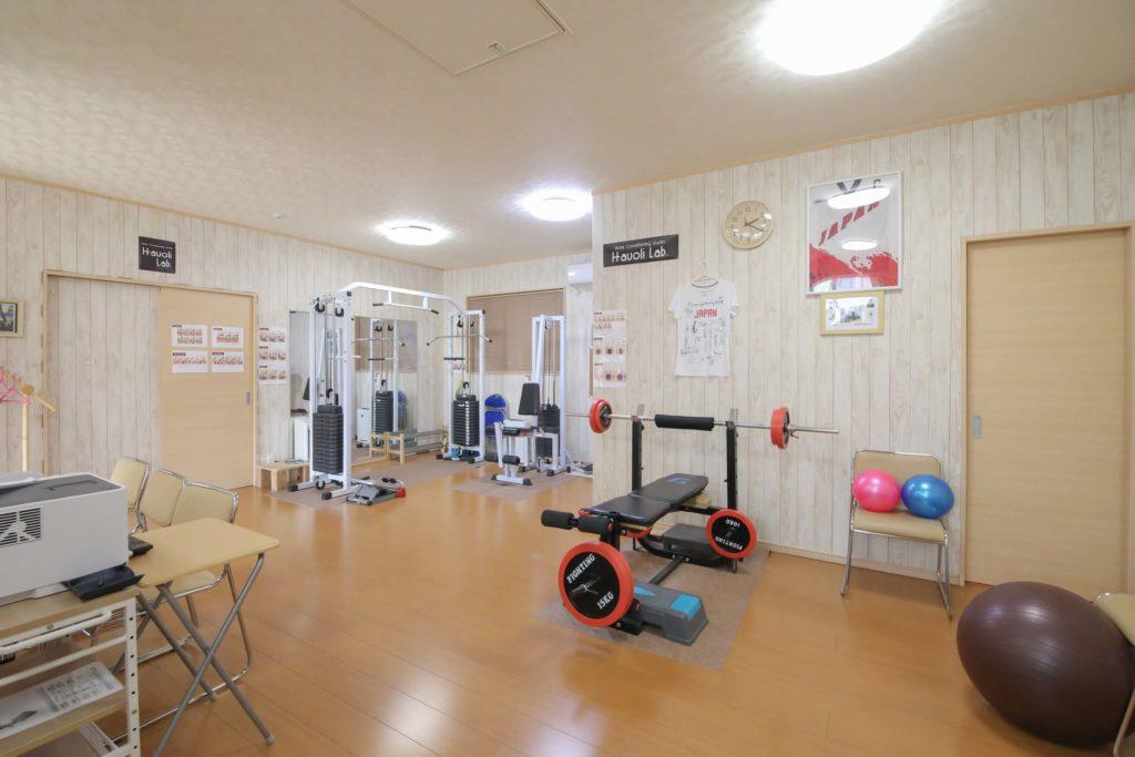 バーベルなどのトレーニング器具やバランスボールが置いてある広々としたハウオリラボの室内写真