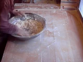 麵打ち台の上で、小麦粉等の粉と水を混ぜたうどんの材料を、両手を使い混ぜ合わせている様子の写真