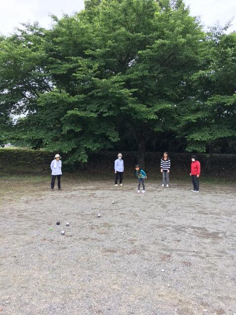 岡本団地ふれあい広場にて、黒や銀色のボールを使いペタンクを楽しむ5名の参加者達の写真