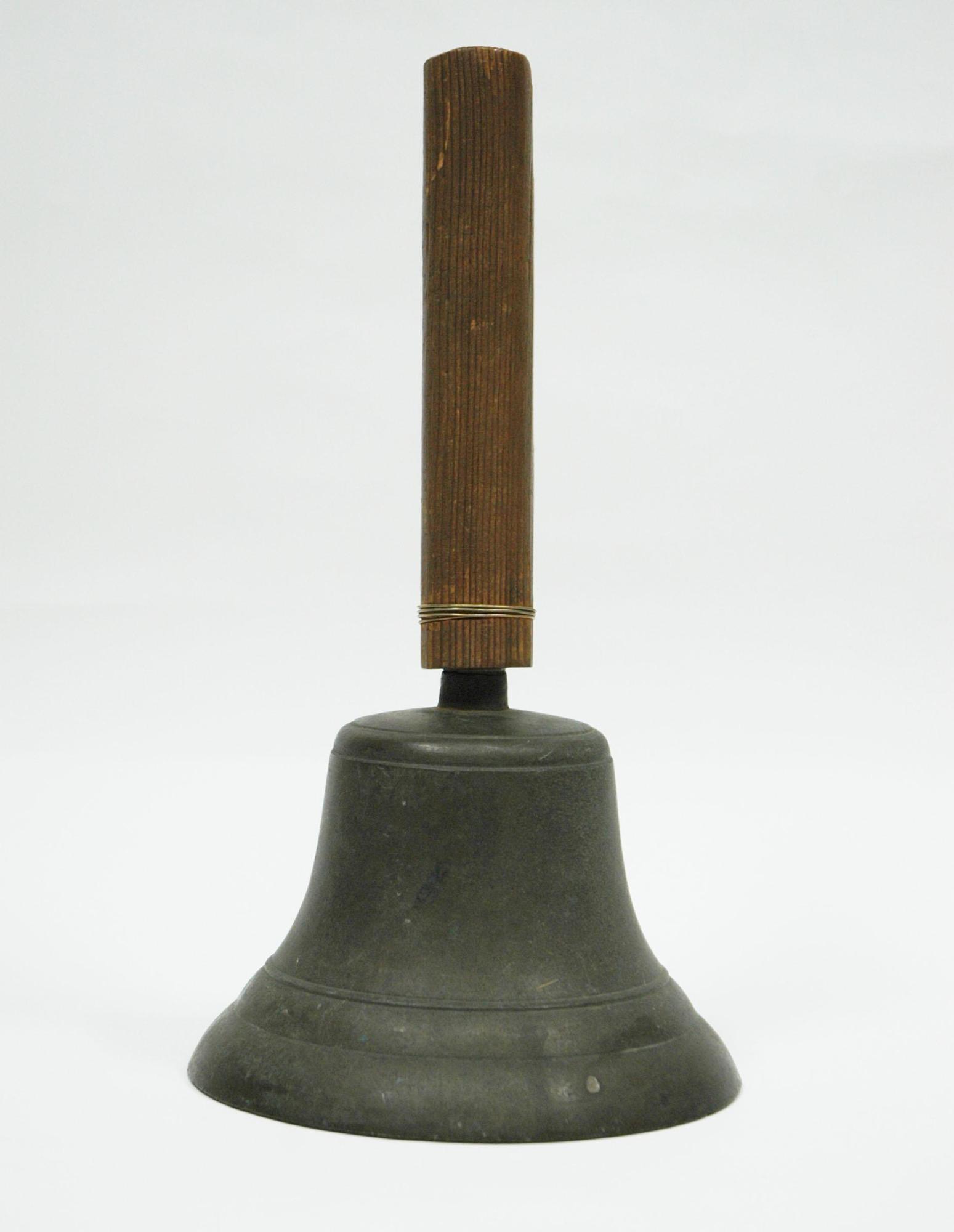 木製の持ち手の下に、銅製で台形のベルの写真