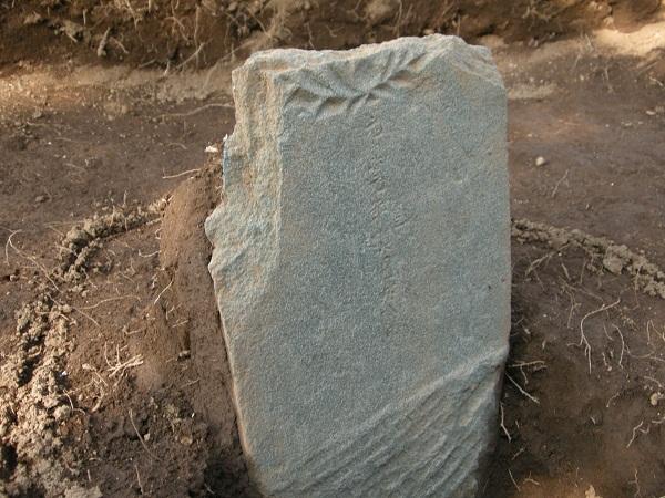 左上が削られた板碑が、立ったまま発掘された写真