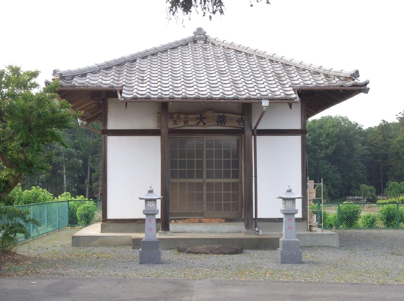 入口に灯籠が2つあり瓦屋根の建物「大薬寺」の外観写真