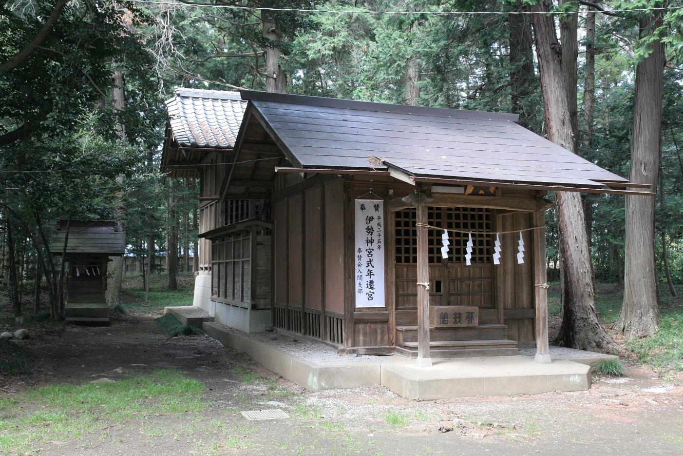 周りが木々に囲まれており、正面の両脇の柱に紐が結ばれ4枚の白い紙垂がつけられている十社神社の外観写真