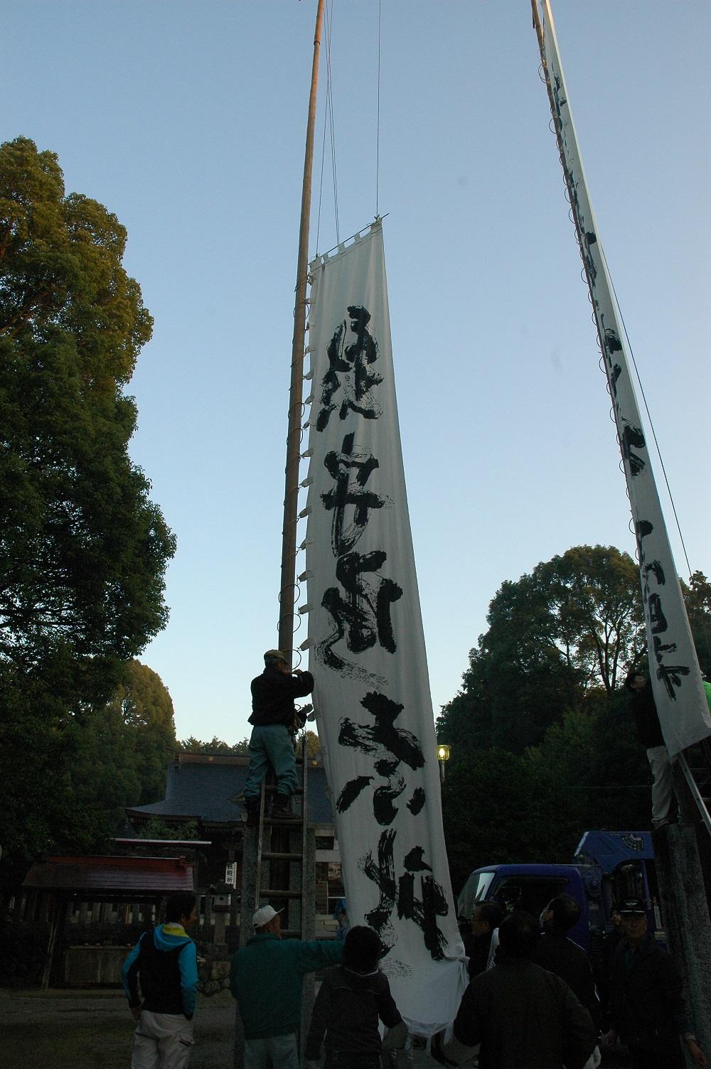 2本の細長い柱に文字が書かれた白旗が立てられている写真