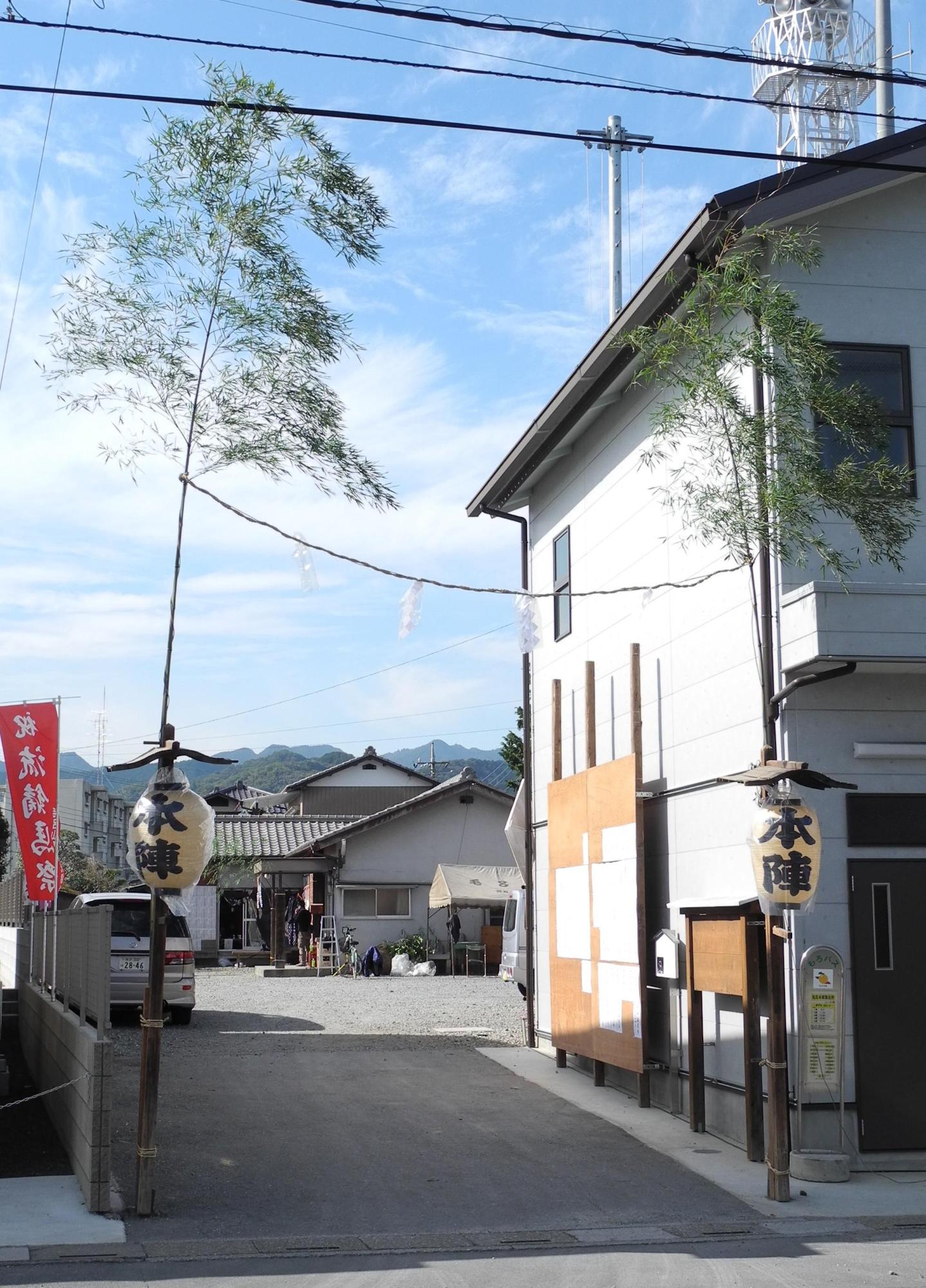 的宿の建物の左側の裏手に続く入り口両脇に、細長い笹の木が立ててあり、中央辺りに本陣と書かれた提灯が掛けられ、笹の葉の辺りに藁紐で繋いでいる写真