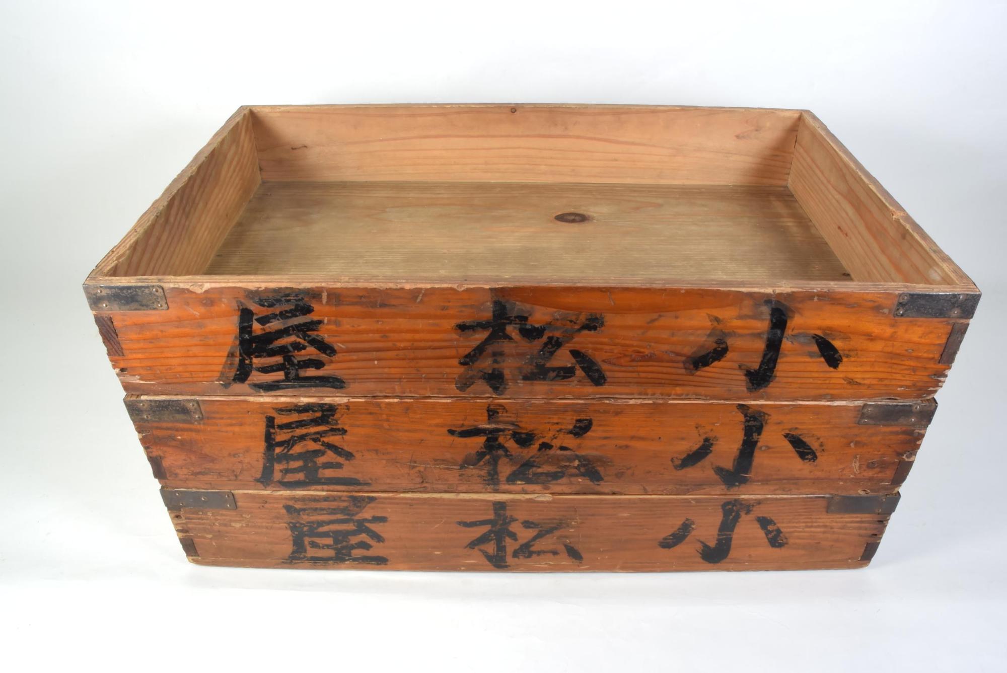 木箱の側面に「小松屋」の文字が書かれており長方形の木箱が3段積み重ねられ、蓋が外されている写真