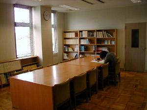 アルミサッシから日が差し込む中図書室の机で勉強している人がいる写真