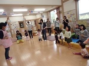 前にいる先生がグーの手を上にあげ、その様子を真似する参加者親子の写真