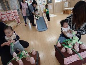 赤ちゃんがお母さんの膝の上に座り、手作りのブドウを引っ張る写真