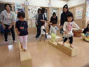 女の子2人がバランスを取りながら、木の平均台を渡る写真