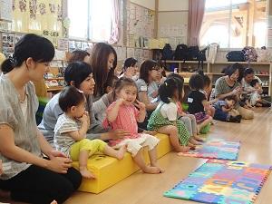ソファに座って手遊びをしている子供たちと母親の写真