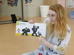ゴリラのイラストが描かれた絵本を指さしながら読み聞かせをしているフリーダ先生の写真