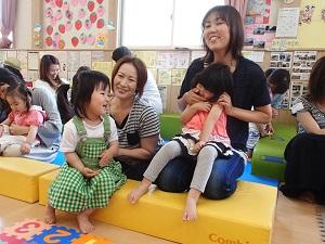 ソファに座っている女の子と母親の膝の上に座っている女の子の写真