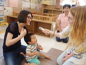 母親にマイクを向けているフリーダ先生とその様子を横で見ている保育士の写真
